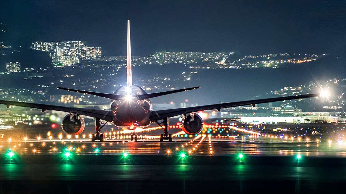 Passenger jet on a runway at night, lit by runway lights